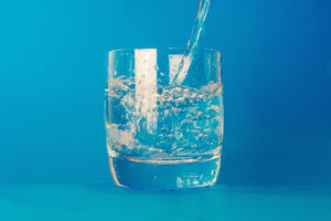 water pouring into a glass on a blue background