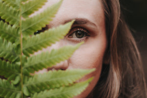 woman holding fern in front of her face