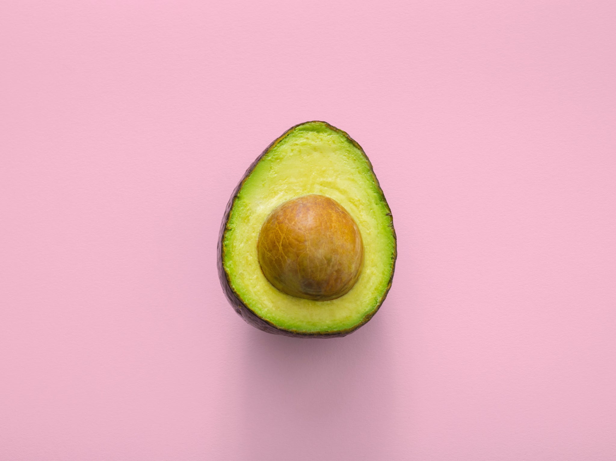 half avocado on a pink background healthy skincare diet